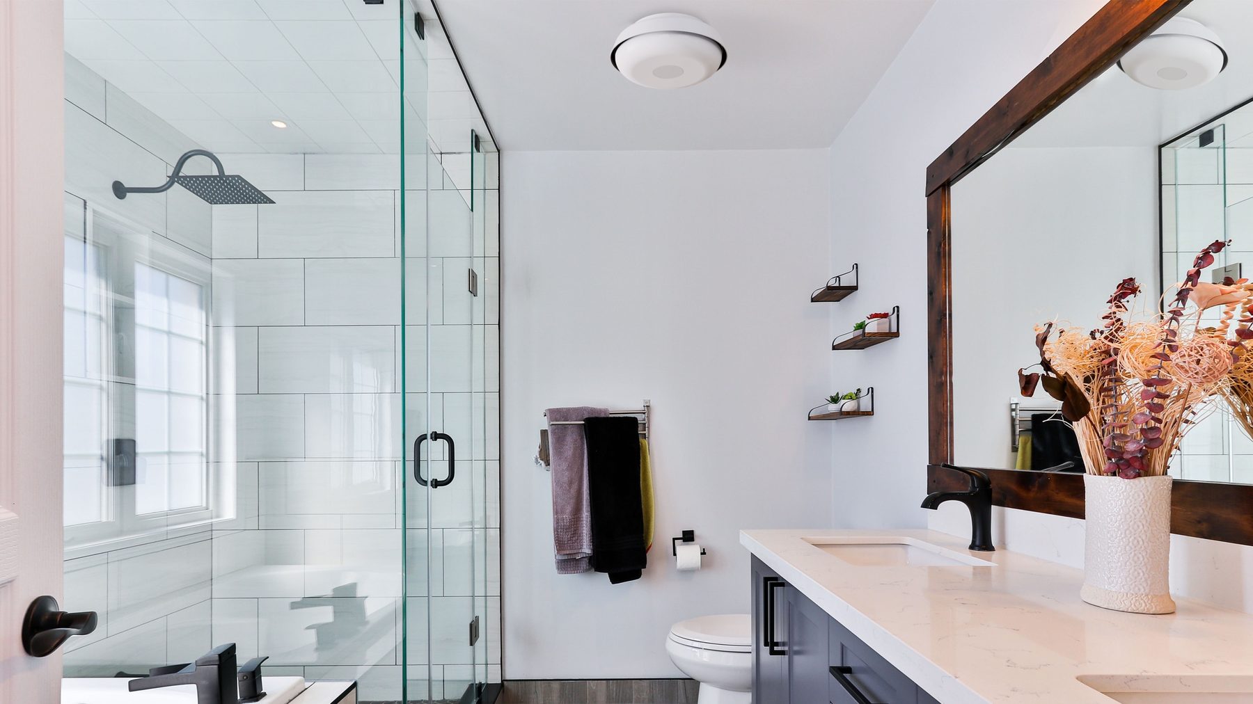 A bright bathroom with a walk-in shower and a Nobita light in the middle of the ceiling.